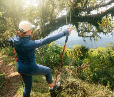 Solo travel, tourism & camping- traveler with hiking sticks up top looking at beautiful summer landscape in the mountains on Africa safari