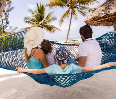 white sand chills Rear view of parents and their small kids relaxing in hammock during summer day on the beach.