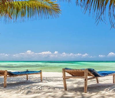 zanzibar chil Beach Lounge chairs under palm tree leaves at the shore of Indian ocean, Zanzibar, Tanzania